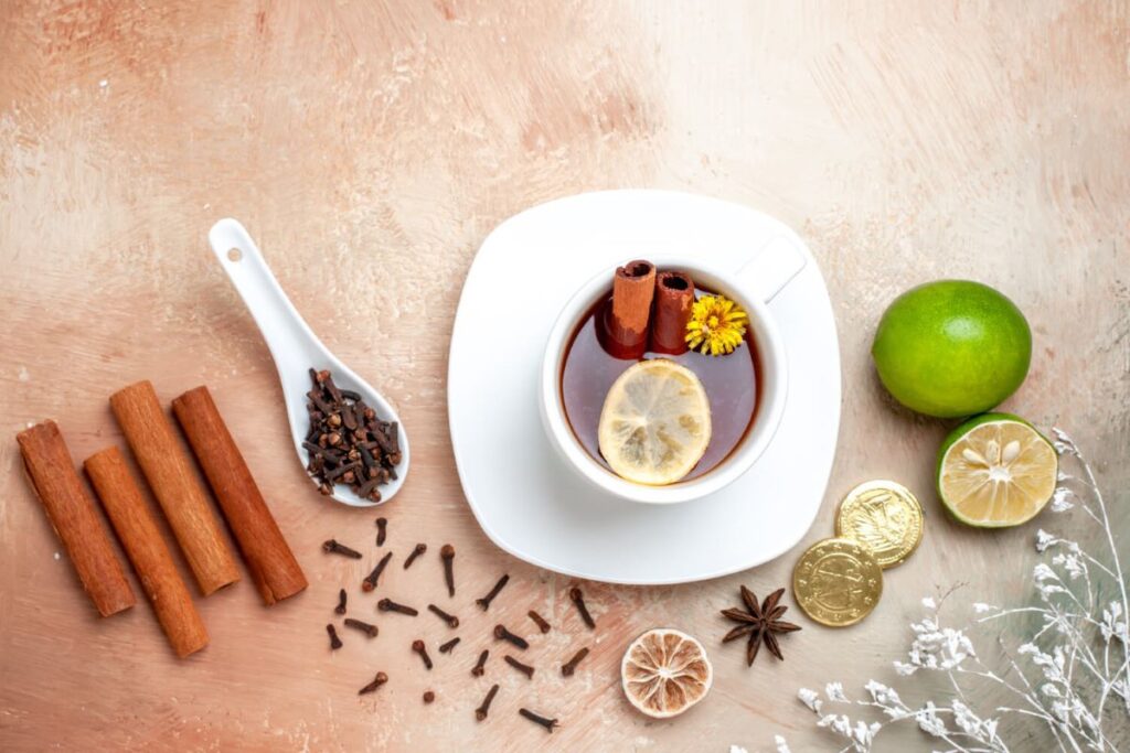 Uma seleção de alimentos que queimam gordura, incluindo pimentas vermelhas, paus de canela, folhas de chá verde e uma raiz de gengibre, dispostos em uma superfície de madeira.